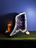Amethyst geode with candles on a dark surface against a blue wall