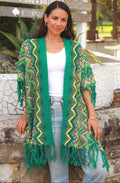 Woman wearing a green patterned cardigan with fringe in an outdoor setting.