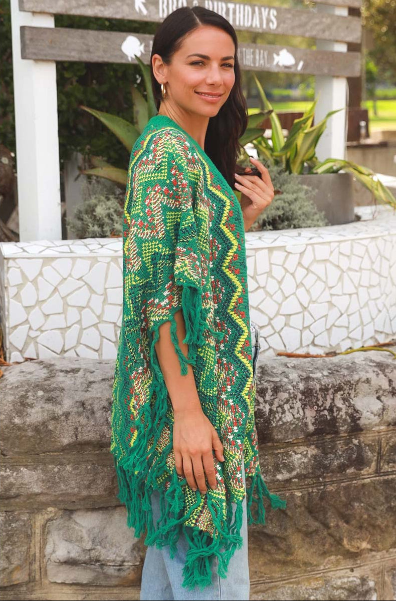 Woman wearing a green patterned kimono-style garment standing outdoors.
