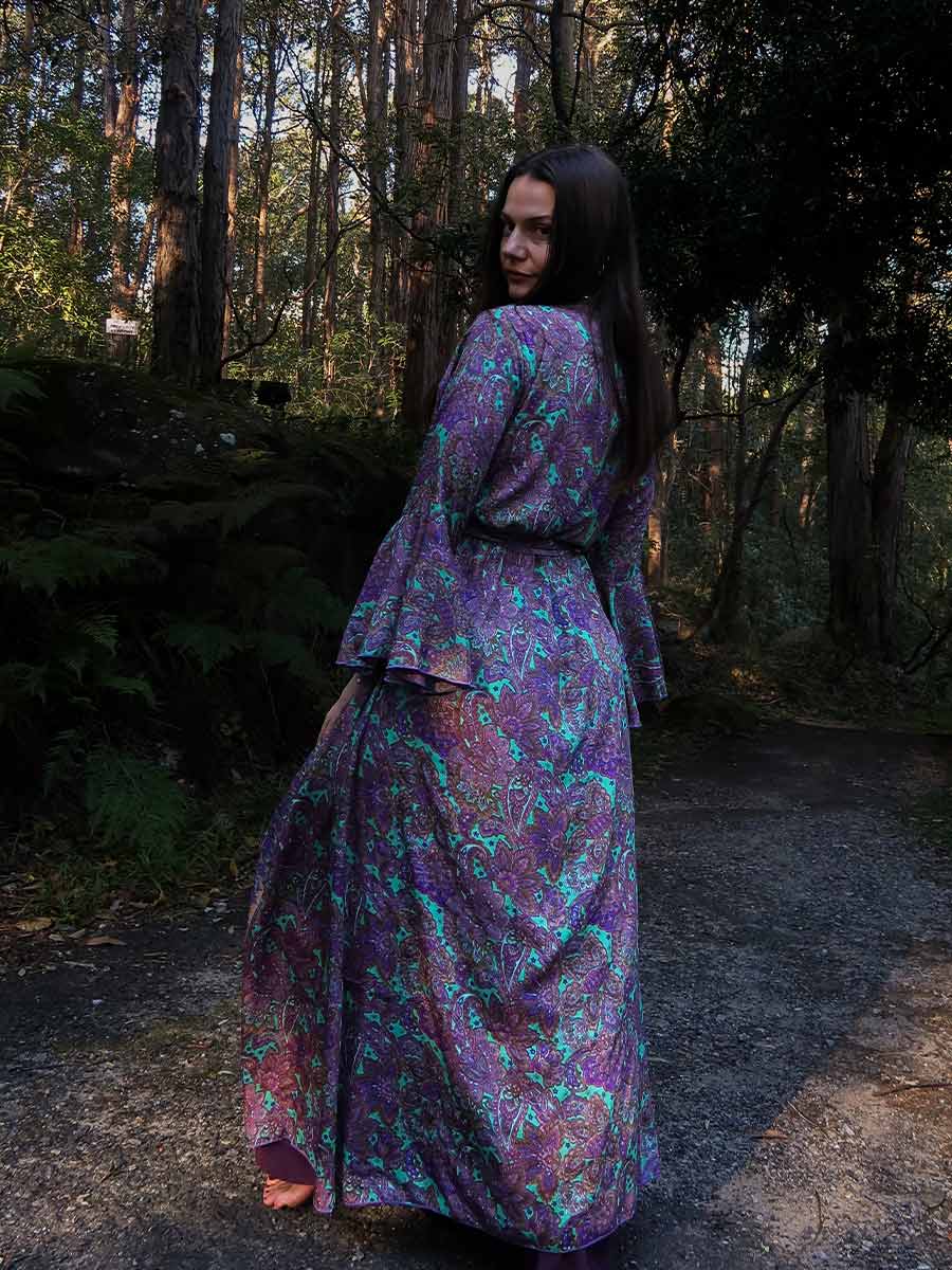 Woman in a purple floral dress standing in a forest