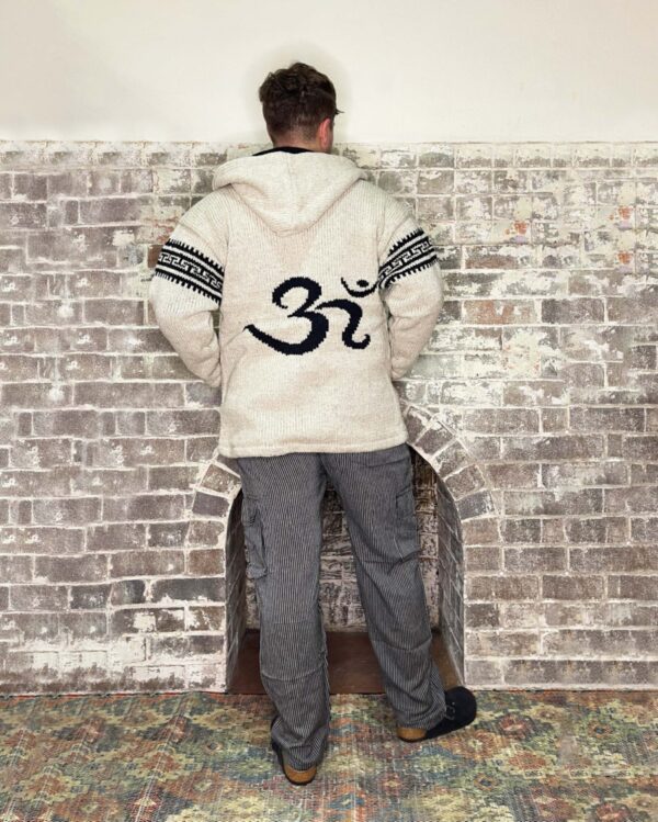 beige coloured woollen zip up jacket, with hood fleece lined with om symbol on back and stripe details