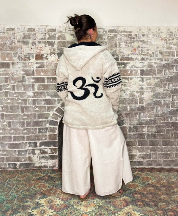 beige coloured woollen zip up jacket, with hood fleece lined with om symbol on back and stripe details