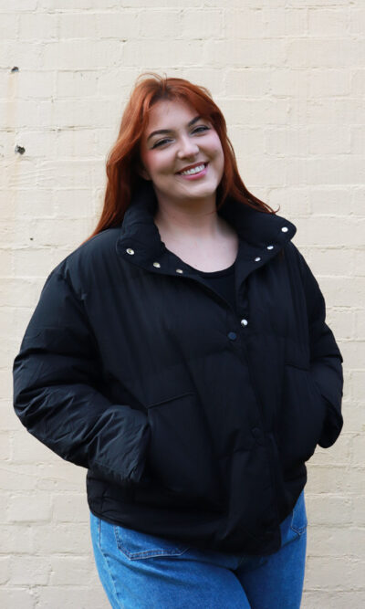 A tall woman wearing a black, puffer jacket.