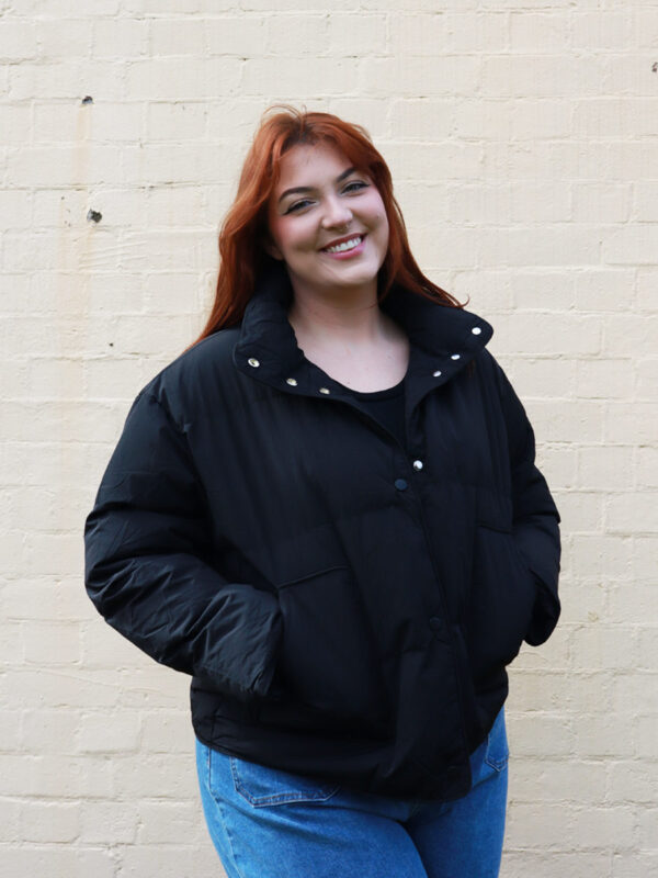 A tall woman wearing a black, puffer jacket.