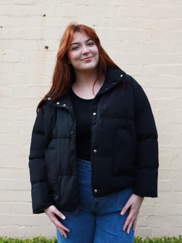 A tall woman wearing a black, puffer jacket.