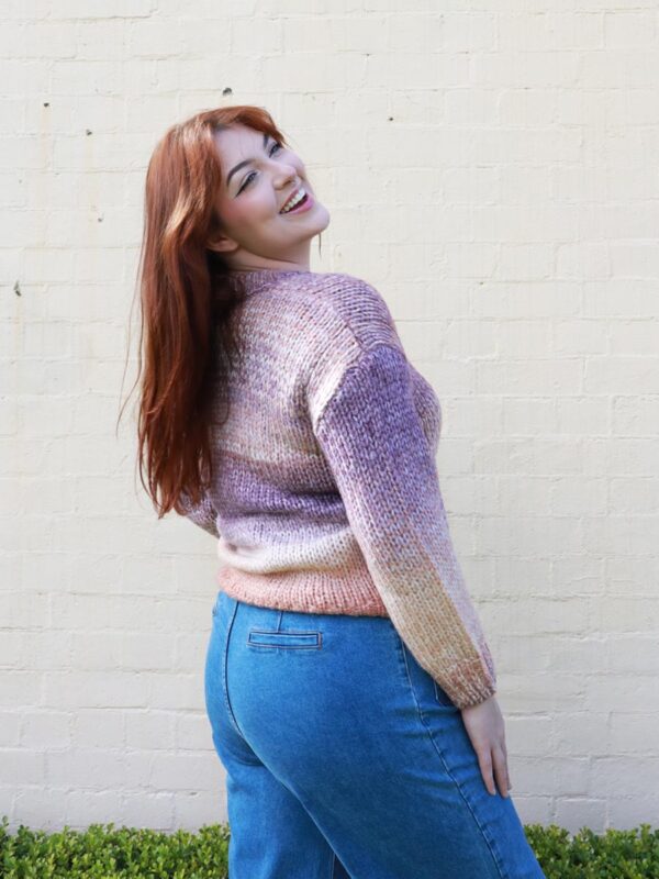 A woman wearing an earthy-toned, multi-coloured, v-neck, knit sweater.