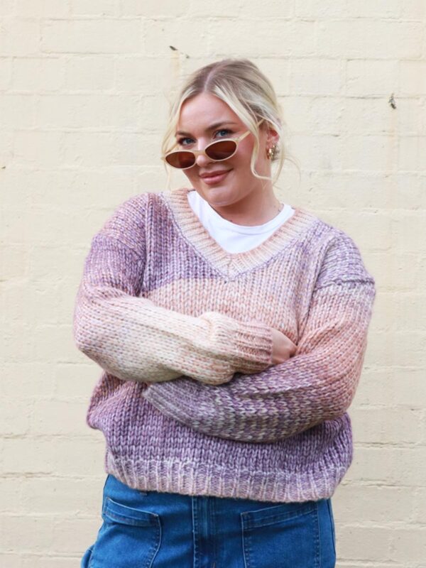 A woman wearing an earthy-toned, multi-coloured, v-neck, knit sweater.