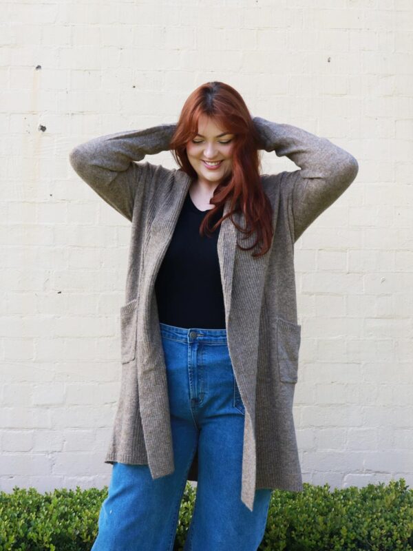 A woman wearing a brown, long, open, knit, cardigan.