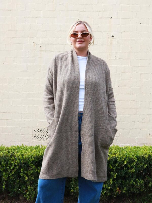 A woman wearing a brown, long, open, knit, cardigan.