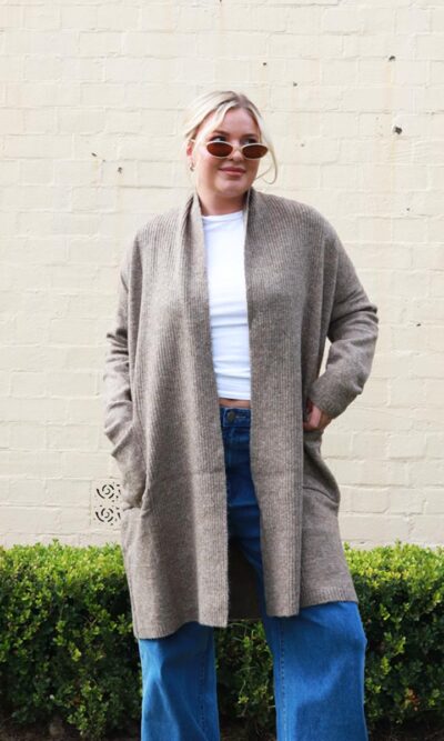 A woman wearing a brown, long, open, knit, cardigan.