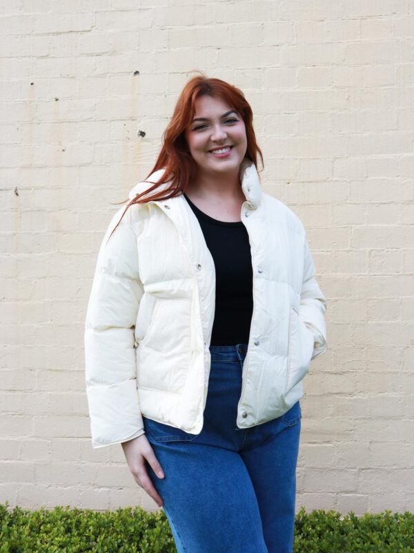 A tall woman wearing a cream, puffer jacket.