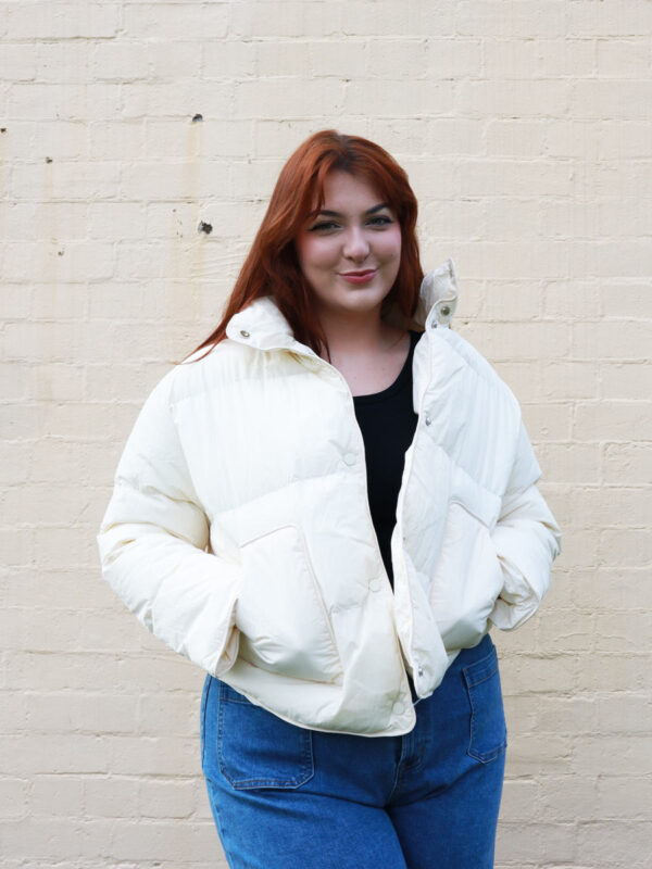 A tall woman wearing a cream, puffer jacket.