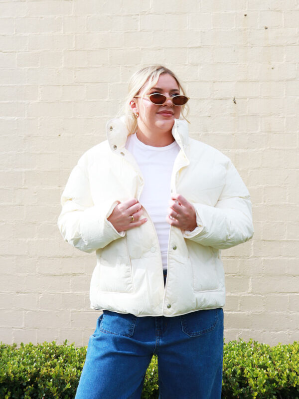 A woman wearing a cream, puffer jacket.