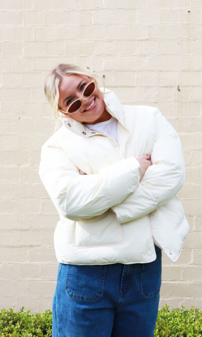 A woman wearing a cream, puffer jacket.