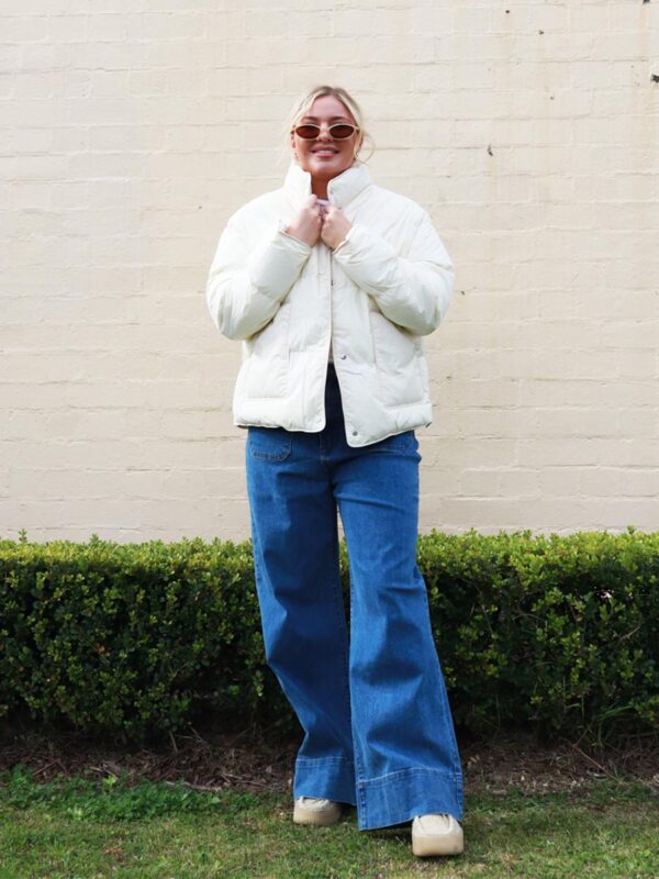 A woman wearing a cream, puffer jacket.