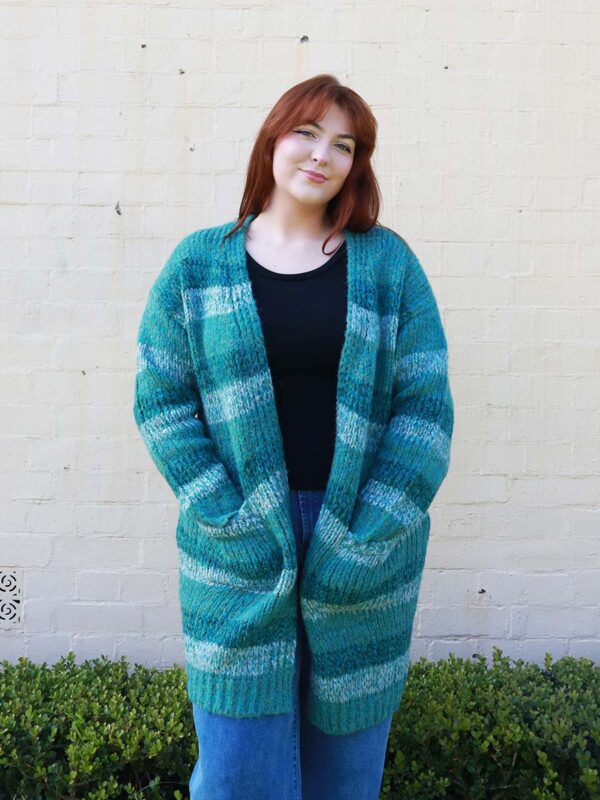 A woman wearing a knitted, green-striped, long, cardigan.