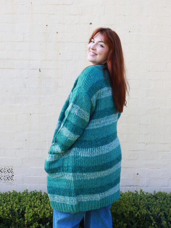 A woman wearing a knitted, green-striped, long, cardigan.