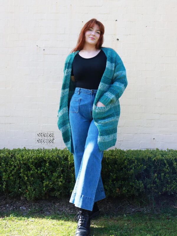 A woman wearing a knitted, green-striped, long, cardigan.