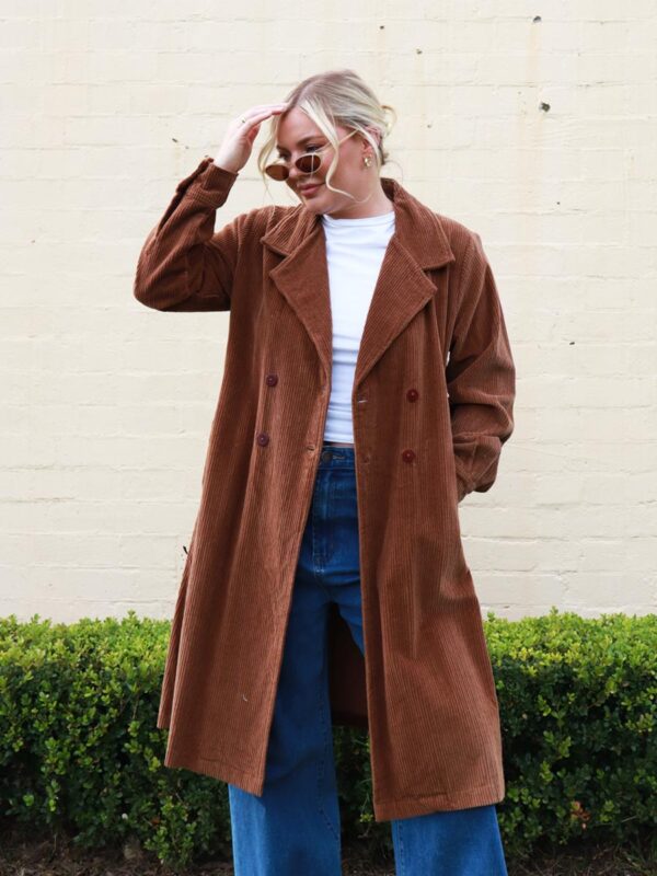 A woman wearing a chocolate brown, knee length corduroy coat.