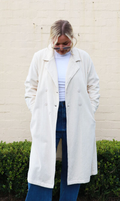 A woman wearing a taupe, knee-length corduroy coat.