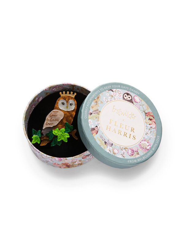 Women's brooch depicting a regal owl perched on a branch wearing a crown. It is shown in a circular box.