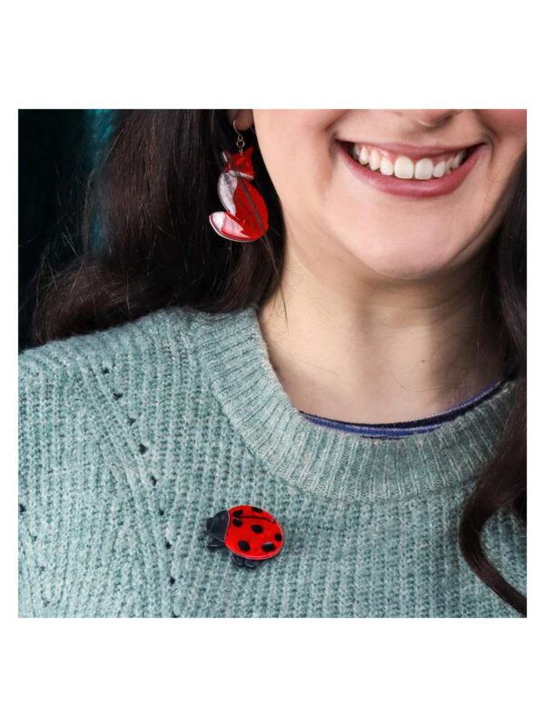 A woman's brooch depicting a red lady beetle pinned to a woman's top.