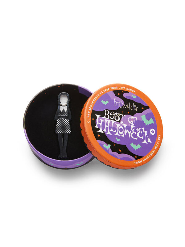 A woman's brooch depicts a Wednesday Adams-inspired character in a circular box.