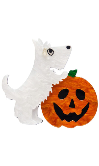 A woman's brooch depicts a white dog with its front legs on a jack-o-lantern.