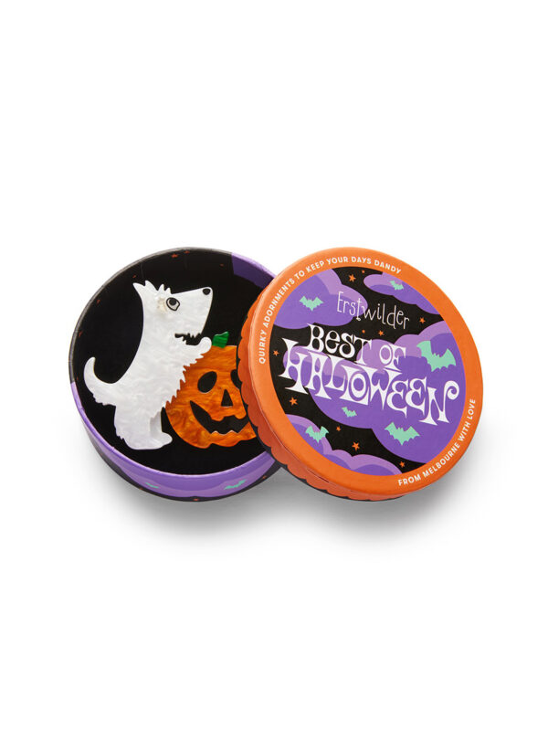 A woman's brooch depicts a white dog with its front legs on a jack-o-lantern in a circular box.