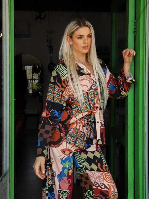 woman standing in a doorway wearing an abstract, printed shirt