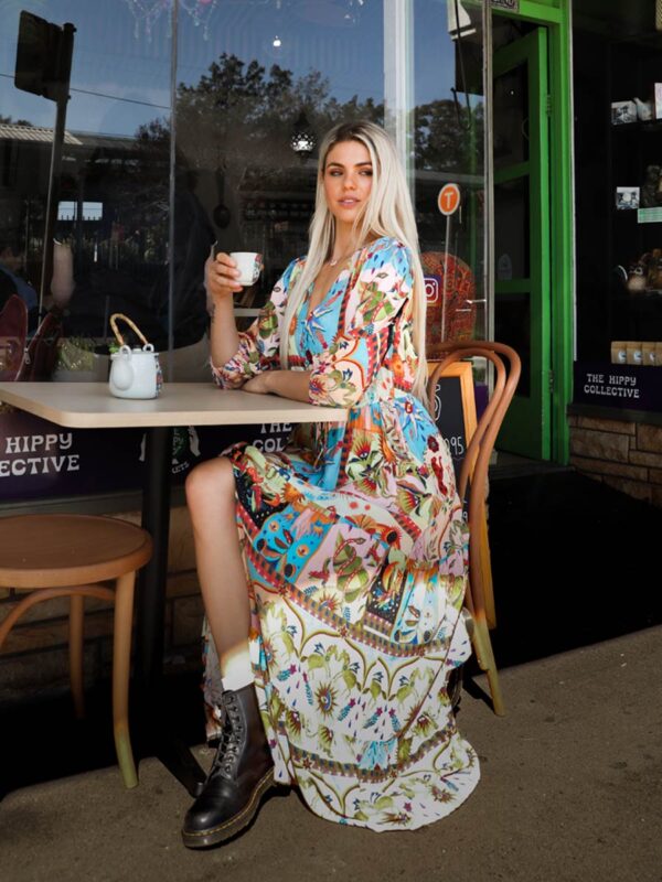 woman sitting at a table drinking tea in a multicoloured bohemian-style dress