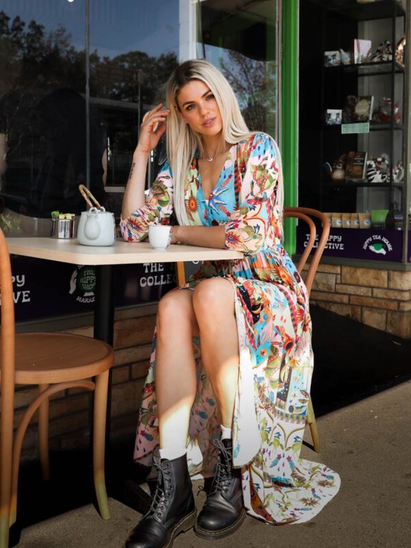 woman sitting at a table drinking tea in a multicoloured bohemian-style dress