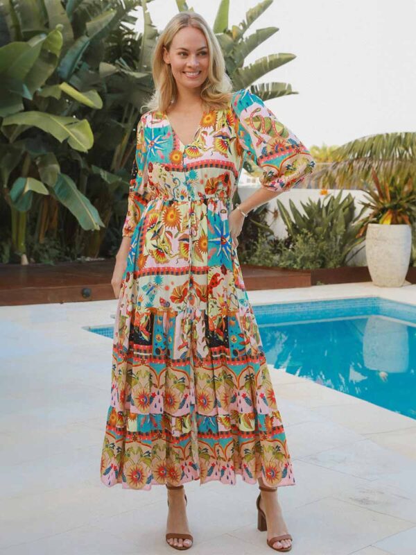 woman stands by a pool wearing a bohemian-style dress