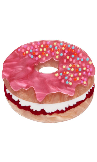 A woman's brooch depicts a pink donut cake with sprinkles.